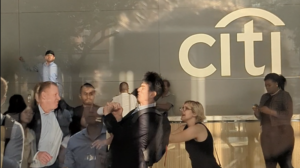 A citi employee punches a protestor in front of a citi sign in the company's lobby